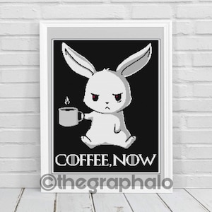 May include: A white bunny with red eyes holding a steaming cup of coffee. The bunny is sitting on a black background with the text "COFFEE, NOW" in white letters below it.