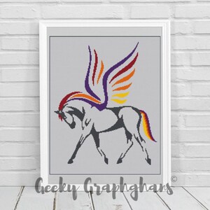 May include: A colorful crochet pattern of a winged horse with a rainbow mane and tail. The horse is standing on a gray background.