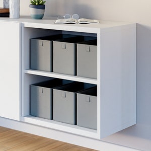 Könnte beinhalten: Ein weißer Schrank mit zwei Regalen, auf denen jeweils sechs graue Stoffaufbewahrungsboxen stehen. Der Schrank hat eine Schiebetür auf der linken Seite.