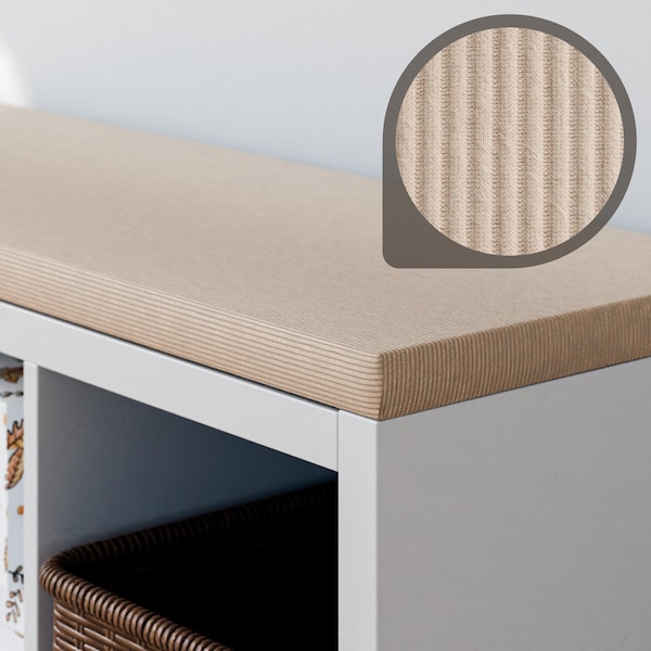 May include: A light brown, textured bench cushion with vertical lines, placed on a white storage unit. The cushion's surface is highlighted in a close-up view, showcasing the detailed texture. A woven basket is visible below.