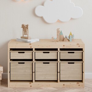 May include: A light-colored wooden storage unit with six drawers and a top shelf. The top shelf displays wooden toys, including a llama, mountains, and a cactus. A cloud-shaped light fixture is mounted on the wall above the unit.