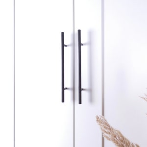 Op de afbeelding: Twee zwarte kastdeurgrepen met een rechthoekige vorm en een gladde afwerking.