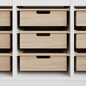 May include: A set of wooden drawers with a light wood grain finish. The drawers have a simple, modern design with a recessed handle. The drawers are set in a white frame, creating a clean and organized storage solution.