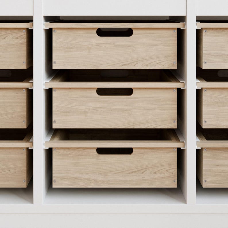 May include: A set of wooden drawers with a light wood grain finish. The drawers have a simple, modern design with a recessed handle. The drawers are set in a white frame, creating a clean and organized storage solution.