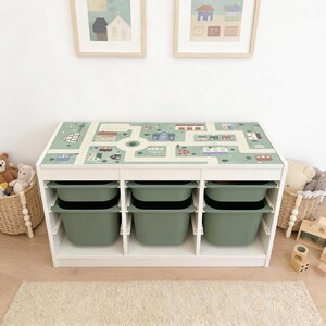 May include: A white rectangular storage unit featuring a top surface printed with a green town map graphic. The unit contains six removable sage green plastic bins arranged in two rows of three, providing organized storage for various items.