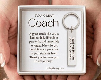 May include: A gift set featuring a silver keychain and a white box with text. The keychain has a rectangular tag with the words "Thank you for your part in my journey." The box reads "To a Great Coach."