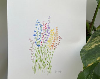 May include: Watercolor painting of colorful wildflowers in shades of blue, purple, yellow, and orange. The flowers have green stems and are arranged in a bouquet. The artist's signature is in the bottom right corner.