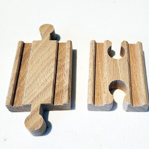 May include: Two wooden train track pieces. One is a straight track and the other is a curved track.