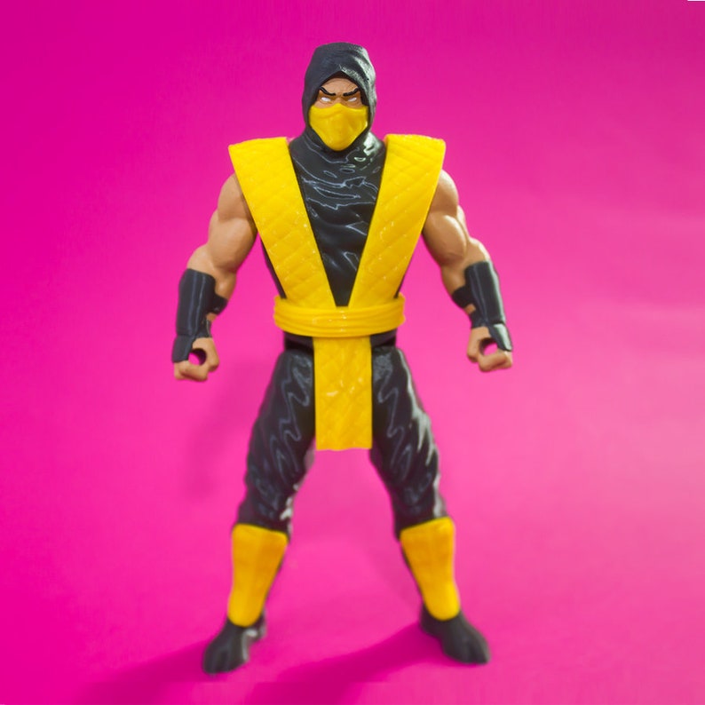 May include: A black and yellow action figure of a ninja warrior. The figure has a black hooded mask with a yellow face mask, a yellow sash, and black pants with yellow accents.