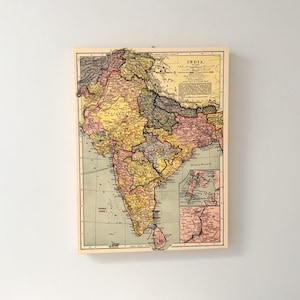 May include: A rectangular wall map of India printed on a light-coloured wooden board. The map features muted yellow, pink, and green regions with black text labels, grid lines, and a detailed inset map of Calcutta in the bottom right corner.