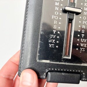 Puede incluir: Un libro de direcciones negro vintage con un selector de letras deslizante. El selector tiene letras de la A a la Z, con una cubierta de pl&aacute;stico transparente. El libro est&aacute; hecho de material negro similar al cuero y tiene forma rectangular.