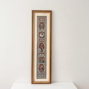 Può includere: Un'opera d'arte da parete rettangolare, alta e stretta, incorniciata in legno dorato. L'immagine presenta una serie verticale di quattro medaglioni ovali contenenti figure classiche in toni terracotta e bianco, separati da pannelli decorativi.