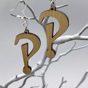 May include: A pair of wooden earrings shaped like question marks. The earrings are brown and have a natural wood grain. They are hanging from silver hooks.