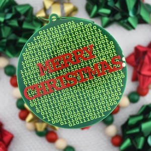 May include: A green Christmas ornament with a binary code pattern and the words "MERRY CHRISTMAS" in red. The ornament is surrounded by green and red bows and a garland of beads.
