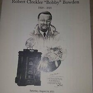 May include: A black and white illustration of Robert Cleckler "Bobby" Bowden, a football coach, holding a football. The illustration is on a white background with the text "Celebrating the Life of Robert Cleckler "Bobby" Bowden 1929-2021" at the top. The text "Saturday, August 14, 2021 Eleven o'clock in the morning Donald L. Tucker Center Tallahassee, Florida" is at the bottom.