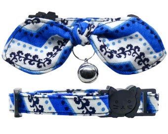May include: Blue and white patterned cat collar with a bow tie and a bell. The collar has a safety buckle with a cat face.
