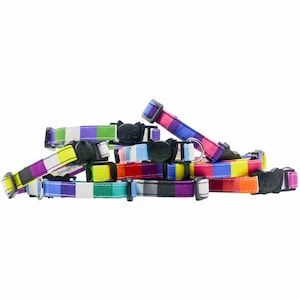 May include: A collection of colorful striped cat collars with a black cat face buckle. The collars are made of fabric and have a variety of colors, including red, orange, yellow, green, blue, purple, and white.