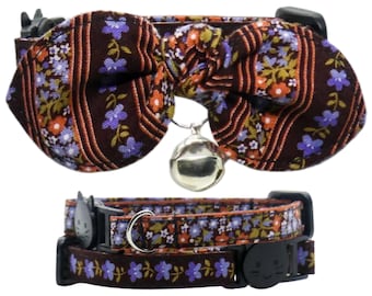 May include: A brown and purple floral cat collar with a matching bow tie and a silver bell. The collar is adjustable and has a safety release buckle.