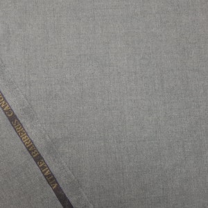 May include: A close-up of a gray fabric with a dark blue label that reads " Vitale Barberis Canonico 1935 ".