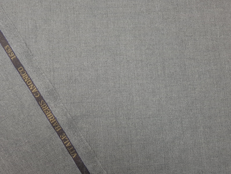 May include: A close-up of a gray fabric with a dark blue label that reads " Vitale Barberis Canonico 1935 ".