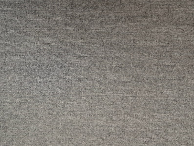 May include: A close-up of a gray textured fabric with a subtle sheen. The fabric has a fine weave and a slightly rough texture.