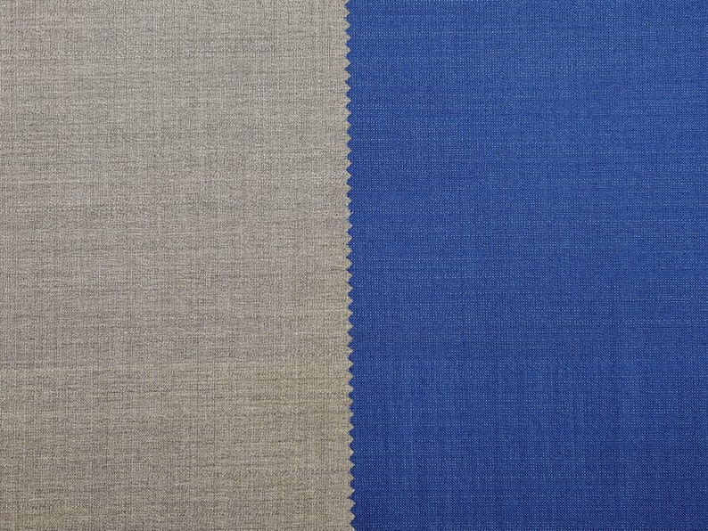May include: Close-up of two fabric swatches, one a light gray and the other a dark blue. The swatches are side-by-side and show the texture of the fabric.