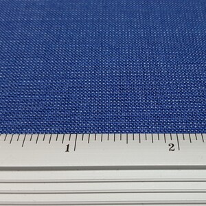 May include: A close-up of a blue fabric with a ruler showing 2 inches.