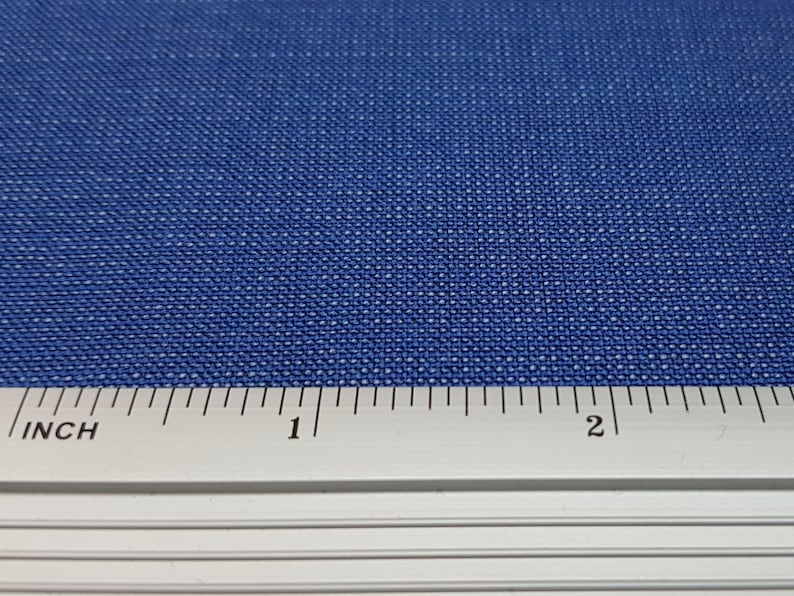 May include: A close-up of a blue fabric with a ruler showing 2 inches.