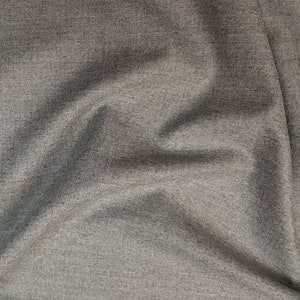 May include: Close-up of a gray, textured fabric with a subtle sheen. The fabric is wrinkled and folded, creating a soft, draping effect.