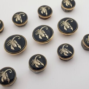 May include: Ten black and gold round buttons with a gold scorpion design.