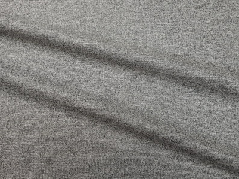May include: Close-up of a gray textured fabric with a subtle diagonal pattern. The fabric has a smooth, soft feel and is slightly wrinkled.