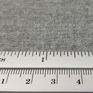 May include: A close-up of a gray, textured surface with a ruler measuring in inches and centimeters. The ruler shows measurements up to 5 centimeters and 2 inches.