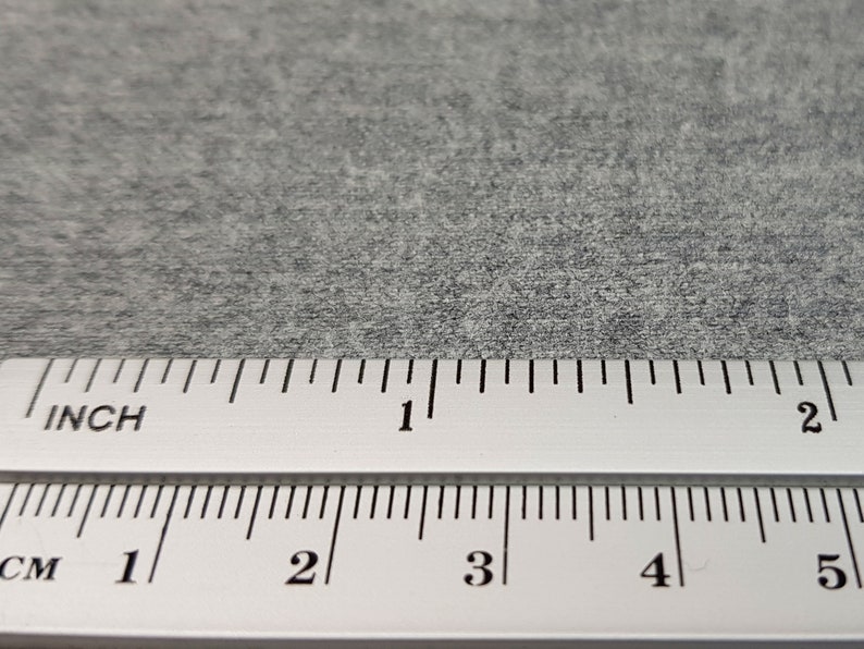 May include: A close-up of a gray, textured surface with a ruler measuring in inches and centimeters. The ruler shows measurements up to 5 centimeters and 2 inches.