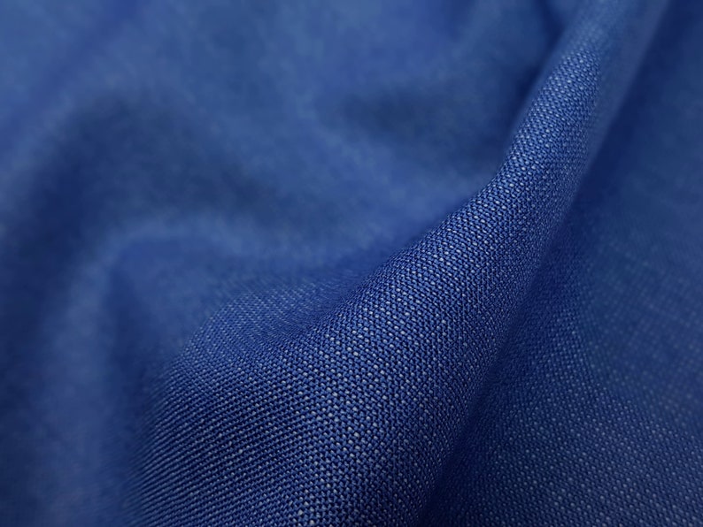 May include: Close-up of a textured blue fabric. The fabric has a subtle woven pattern and a smooth, soft feel.