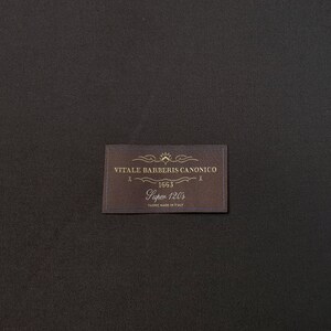 Puede incluir: Una etiqueta marr&oacute;n con texto dorado que dice "VITALE BARBERIS CANONICO 1663 Super 120's FABRIC MADE IN ITALY".
