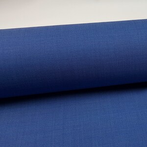 May include: A roll of blue fabric. The fabric has a smooth, even texture.
