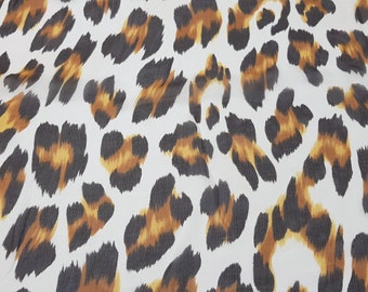 May include: White fabric with a brown and black leopard print pattern.