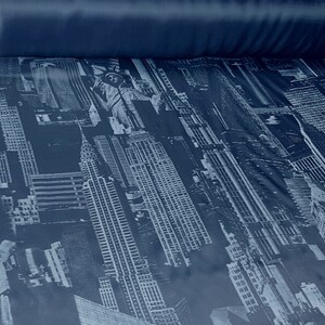 May include: A blue fabric with a white and grey print of the New York City skyline, including the Statue of Liberty.