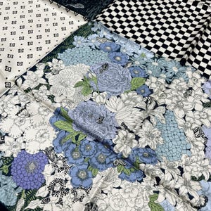 May include: A silk scarf with a patchwork design featuring floral patterns in shades of blue, white, and green. The scarf also includes a black and white checkered pattern and a pattern of small white squares with black details.