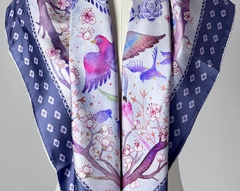 May include: A square scarf with a bird and floral design. The scarf features a white background with purple and pink birds, branches, and flowers. The border is a dark blue with a white floral pattern.