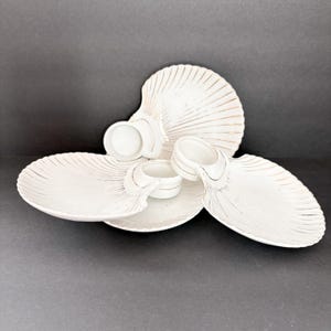 May include: White ceramic serving dish shaped like a seashell with three smaller bowls. The dish has a gold-colored design.