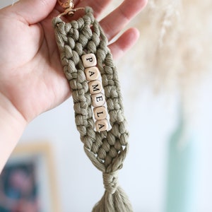Puede incluir: Un llavero de macram&eacute; verde con un borla y cuentas de madera que deletrean el nombre "PAMELA".