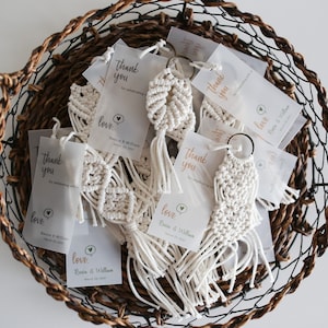 May include: A wicker basket filled with white macrame keychains with a small tag that says "Thank you" and "Love,  [Bride's name] & [Groom's name]"