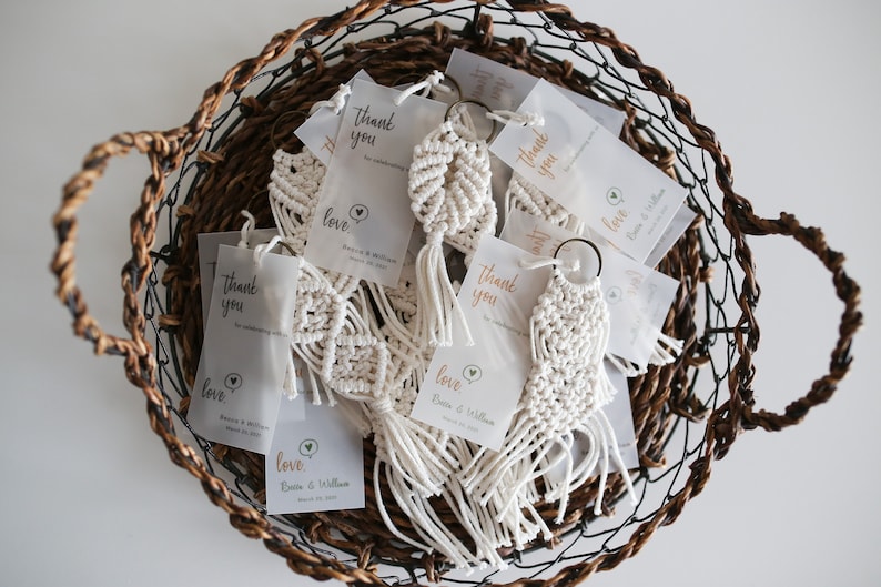 May include: A wicker basket filled with white macrame keychains with a small tag that says "Thank you" and "Love,  [Bride's name] & [Groom's name]"
