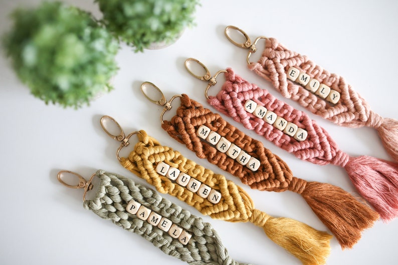 Puede incluir: Cinco llaveros de macram&eacute; de colores con cuentas de letras de madera que deletrean los nombres "Pamela", "Lauren", "Martha", "Amanda" y "Emily".