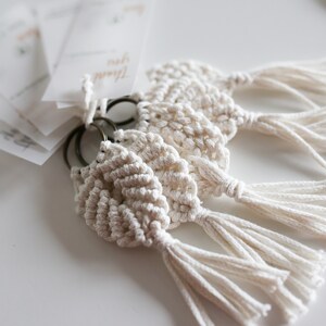 May include: Three white macrame keychains with tassels attached to a silver key ring.