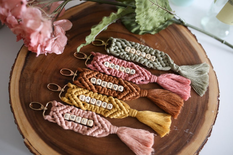 Puede incluir: Cinco llaveros de macram&eacute; de colores con cuentas de madera que deletrean los nombres "Emily", "Lauren", "Martha", "Amanda" y "Pamela".
