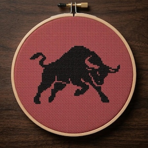 Peut inclure: Broderie au point de croix dans un cercle en bois représentant un taureau noir sur fond rouge. Le taureau est représenté en pleine charge. La broderie est un artisanat fait à la main.