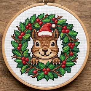 Può includere: Ricamo a punto croce di uno scoiattolo marrone con un cappello da Babbo Natale, incorniciato da una ghirlanda di agrifoglio verde con bacche rosse. Il ricamo è in un telaio di legno, perfetto per le feste.