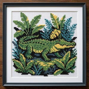 Peut inclure: Broderie au point de croix d'un alligator vert et jaune dans un cadre. L'œuvre encadrée présente un motif détaillé du reptile entouré d'un feuillage vert, jaune et bleu luxuriant. L'œuvre est encadrée dans un cadre en bois noir.